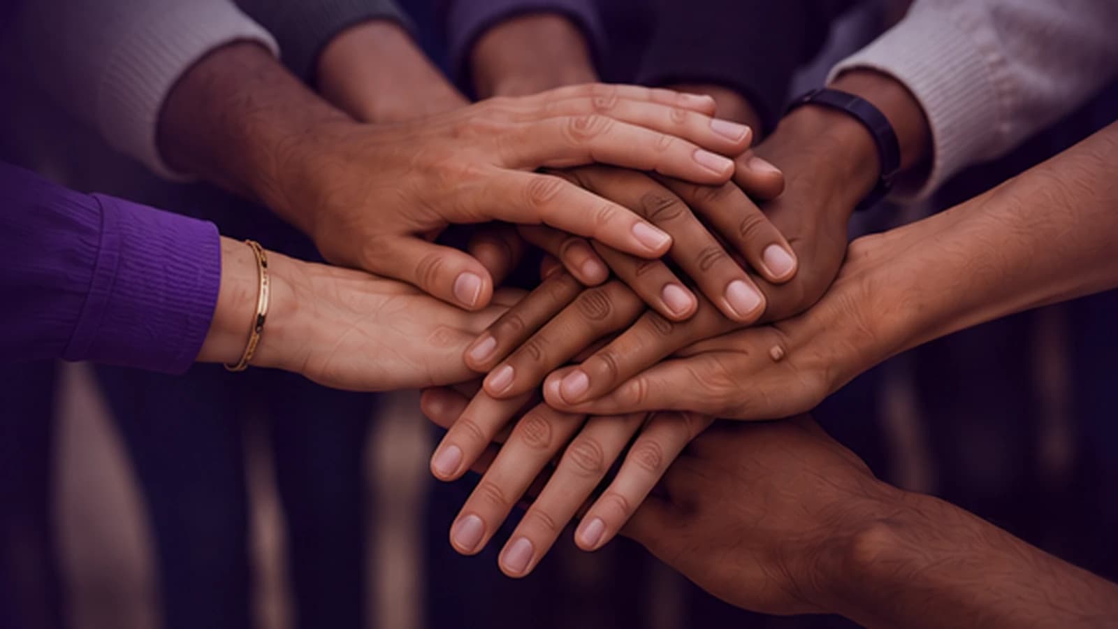A group joins their hands together in a gesture of partnership.